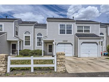 Charming townhouse with a well-maintained lawn, white picket fence, and attached garage at 12332 Colorado Blvd # 30, Thornton, CO 80241