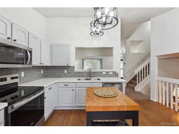 Bright kitchen features white cabinets, stainless steel appliances, tile backsplash, and center island at 12753 Buckhorn Creek St, Parker, CO 80134