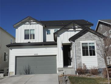 Charming two-story home featuring a stone facade, gray garage door, and well-maintained landscaping at 5223 Gray Wolf Ln, Castle Rock, CO 80104