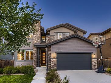 Charming two-story home with a stone facade, gray siding, and a basketball hoop on the driveway at 10968 Pastel Pt, Parker, CO 80134