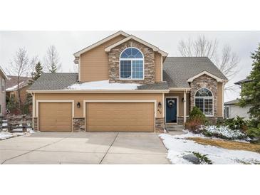 Charming two-story home featuring a three-car garage, stone accents, and a well-maintained front yard with wintery landscaping at 477 Saber Creek Dr, Monument, CO 80132