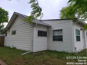 White house with windows and a nice yard surrounded by trees at 4990 Hooker St, Denver, CO 80221