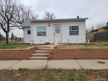 Charming single-story home featuring a well-manicured lawn and a welcoming front porch at 4990 Hooker St, Denver, CO 80221