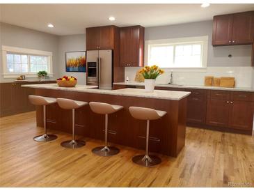 Modern kitchen boasts stainless steel appliances, a center island with seating, and wood floors at 4990 Hooker St, Denver, CO 80221