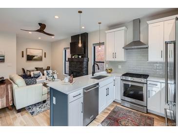 Modern kitchen featuring white cabinets, stainless steel appliances, and a stylish island with seating at 2846 Champa St, Denver, CO 80205