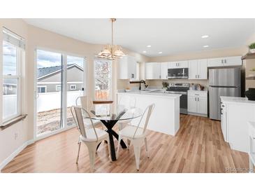 Eat-in kitchen with bright white cabinets, stainless appliances, and sliding glass door to the back yard at 205 Hawthorn St, Frederick, CO 80530