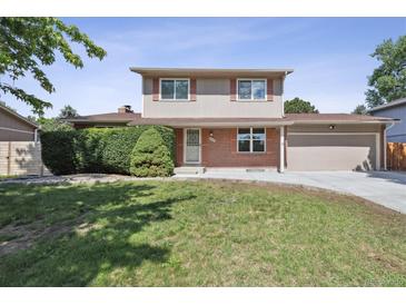 Charming two-story home with manicured lawn, brick accents, and attached garage on a sunny day at 8445 Lamar Dr, Arvada, CO 80003