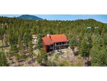 Beautiful mountain home featuring a unique red roof and surrounded by lush greenery and trees at 116 Ramona Rd, Golden, CO 80403