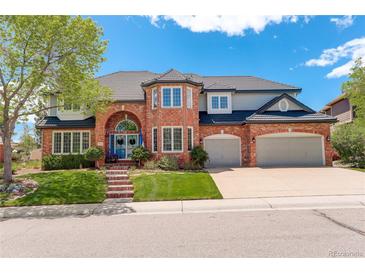 Two-story brick home featuring an arched entryway, manicured lawn, and attached two-car garage at 9141 Roundtree Dr, Highlands Ranch, CO 80126