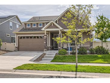 Charming two-story home featuring stone accents, neutral siding, a well-manicured lawn, and an attached two-car garage at 5495 Espana Ct, Denver, CO 80249