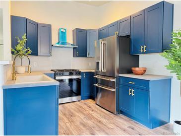 This stylish kitchen features blue cabinets, stainless steel appliances, and modern countertops at 8468 Thunder Ridge Way # 202, Highlands Ranch, CO 80126