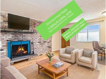 Cozy living room with brick fireplace, hardwood floors, and modern furniture at 155 S Pennsylvania St # 311, Denver, CO 80209
