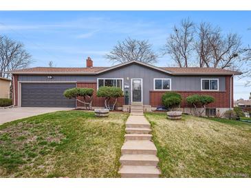 Charming ranch-style home features brick accents, a well-manicured lawn, and a concrete pathway to the front door at 12323 W Connecticut Dr, Lakewood, CO 80228