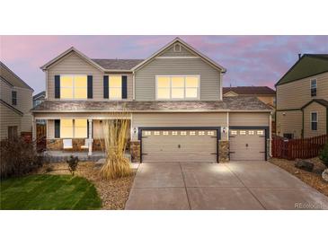 Charming two-story home featuring a three car garage, complemented by decorative stone and manicured lawn at 10158 Granby St, Commerce City, CO 80022