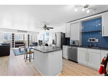 Bright, updated kitchen featuring stainless steel appliances, an island, and vibrant blue backsplash tiles at 1121 Albion St # 210, Denver, CO 80220