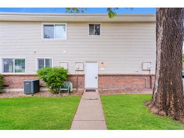 Two-story townhouse featuring neutral siding, brick accents, a well-manicured lawn, and a charming walkway to the front door at 9005 E Lehigh Ave # 16, Denver, CO 80237