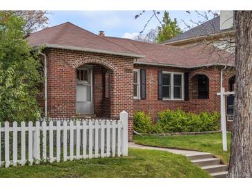 Charming brick home featuring a manicured front yard and a classic white picket fence at 652 N Gilpin St, Denver, CO 80218
