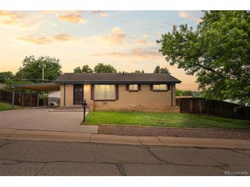 Charming brick home featuring a carport and well-maintained front yard with mature landscaping at 6627 Eaton St, Arvada, CO 80003