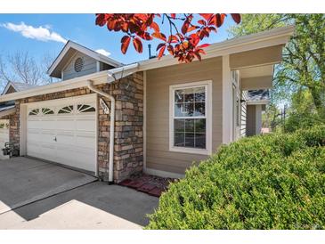 Charming home exterior with stone accents, lush landscaping, and a convenient two-car garage at 6803 W Yale Ave, Lakewood, CO 80227
