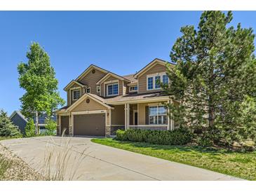 Two-story home with a three car garage, covered porch, manicured lawn and mature landscaping at 1905 Graphite Ct, Castle Rock, CO 80108