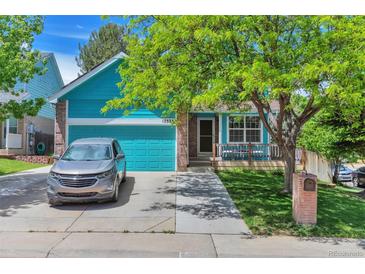 Charming exterior view of a two-story home with a lush green lawn and blue garage door at 12333 Newport Ct, Brighton, CO 80602