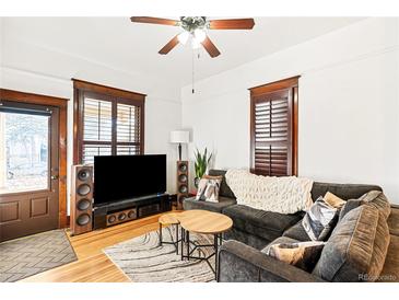 Inviting living room featuring a comfortable gray sofa, wood floors, and abundant natural light at 3737 Jason St, Denver, CO 80211