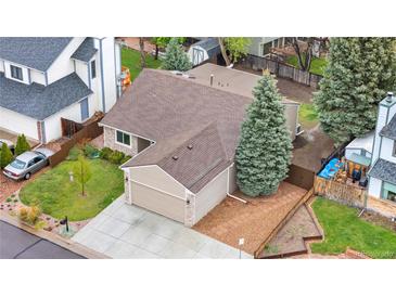 Aerial view of a two story tan home with a mature evergreen tree and a concrete driveway to a two car garage at 9960 Garland Ln, Broomfield, CO 80021