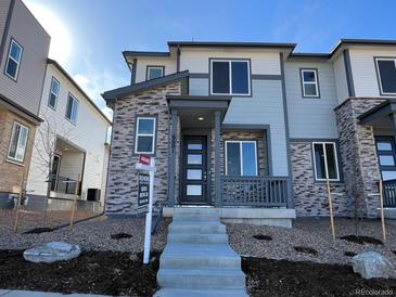 Modern two-story townhome with a stone facade, a front porch and professional landscaping at 6601 N Netherland St, Aurora, CO 80019