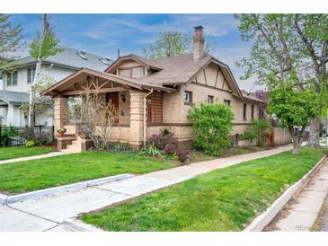 Charming brick home featuring a cozy front porch, manicured lawn, and mature trees at 401 S Williams St, Denver, CO 80209