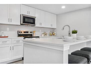 Modern kitchen with white cabinets, quartz countertops, and island at 9300 Grove St, Westminster, CO 80031