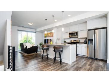 Bright, modern living space with open kitchen, bar seating, stainless appliances, and hardwood floors at 5630 W 11Th Pl, Lakewood, CO 80214
