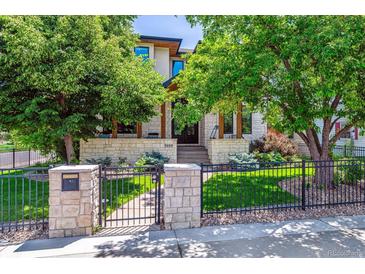 Charming home with stone accents, lush landscaping, and a wrought iron fence creating inviting curb appeal at 2600 S Adams St, Denver, CO 80210