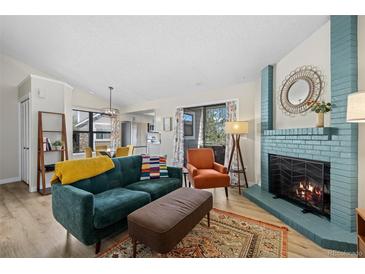 Bright living room featuring a blue fireplace, hardwood floors, and open access to the kitchen at 8378 S Upham Way # B305, Littleton, CO 80128