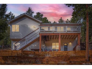 Charming home with a spacious deck and wooden fence, set against a backdrop of lush trees at 13495 Shiloh Rd, Conifer, CO 80433