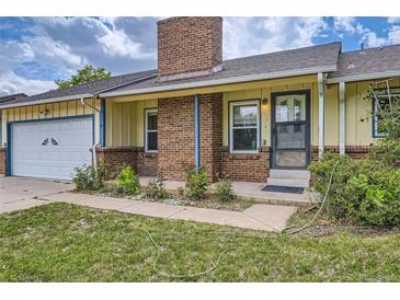 Charming home with a brick chimney and lush green lawn and walkway to the front door at 1431 S Chambers Cir, Aurora, CO 80012