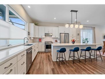 Bright, modern kitchen with stainless steel appliances, white cabinets, and quartz countertops offers ample space at 5189 Vivian St, Wheat Ridge, CO 80033