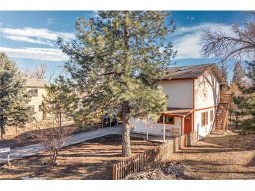 Charming two-story home featuring white siding, red trim, mature trees, and a quaint picket fence at 11970 W Pleasant Ave, Lakewood, CO 80401