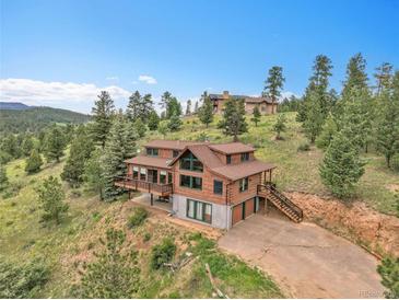 An expansive exterior view showcasing a beautiful cabin-style home nestled among lush greenery and trees at 25704 Shiloh, Conifer, CO 80433