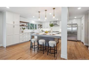 Bright kitchen boasts a large center island, stainless steel appliances, and sleek, white cabinetry at 7866 S Valentia Way, Centennial, CO 80112
