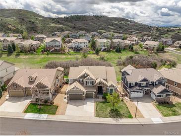 Stunning aerial view of suburban homes boasting meticulous landscaping and mountain views under a cloudy sky at 5010 Persimmon Ln, Castle Rock, CO 80109