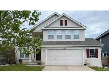Charming two-story home features an attached two car garage, manicured lawn, and decorative shutters at 8769 S Dudley St, Littleton, CO 80128