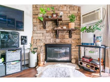 Cozy living room featuring a stone fireplace, wooden shelves, modern decor, and comfortable seating at 10150 E Virginia Ave # 19-303, Denver, CO 80247