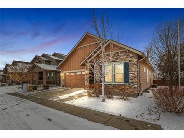 Charming single-Gathering home featuring a beautiful mix of stone and wood accents with a two-car garage and snow-covered front yard at 6592 Club Villa Rd, Parker, CO 80134