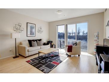 Bright living room featuring a cozy seating area and a sliding glass door to the balcony at 1438 Little Raven St # 306, Denver, CO 80202