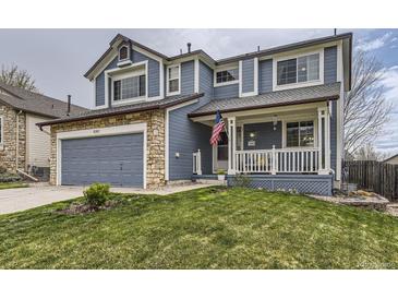 Charming two-story blue home with a stone-accented garage and a welcoming front porch at 10987 Cannonade Dr, Parker, CO 80138
