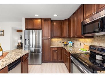 Well-lit kitchen features dark wood cabinets, granite countertops, and stainless steel appliances at 2363 Ranch Dr, Westminster, CO 80234