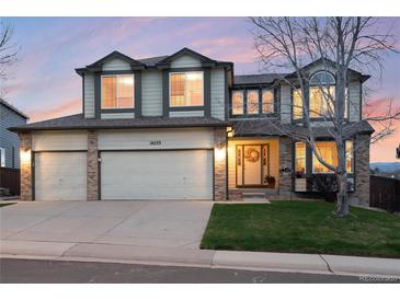 Charming two-story home featuring a three-car garage, a welcoming front porch, and manicured lawn at 10233 Silver Maple Cir, Highlands Ranch, CO 80129