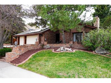 Charming brick home featuring a well-maintained lawn and two-car garage, complete with mature landscaping at 5531 S Telluride Ct, Centennial, CO 80015
