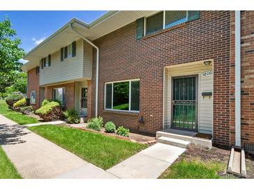 Inviting brick townhome featuring a well-maintained lawn and charming landscaping at 3806 S Yosemite St, Denver, CO 80237