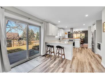 Bright kitchen with white cabinets, granite countertops, stainless steel appliances, and sliding glass door to backyard at 9749 Meade Cir, Westminster, CO 80031